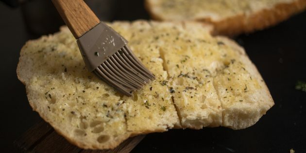 So machen Sie Knoblauchkäse-Croutons: Verteilen Sie Butter auf der gesamten Brotoberfläche